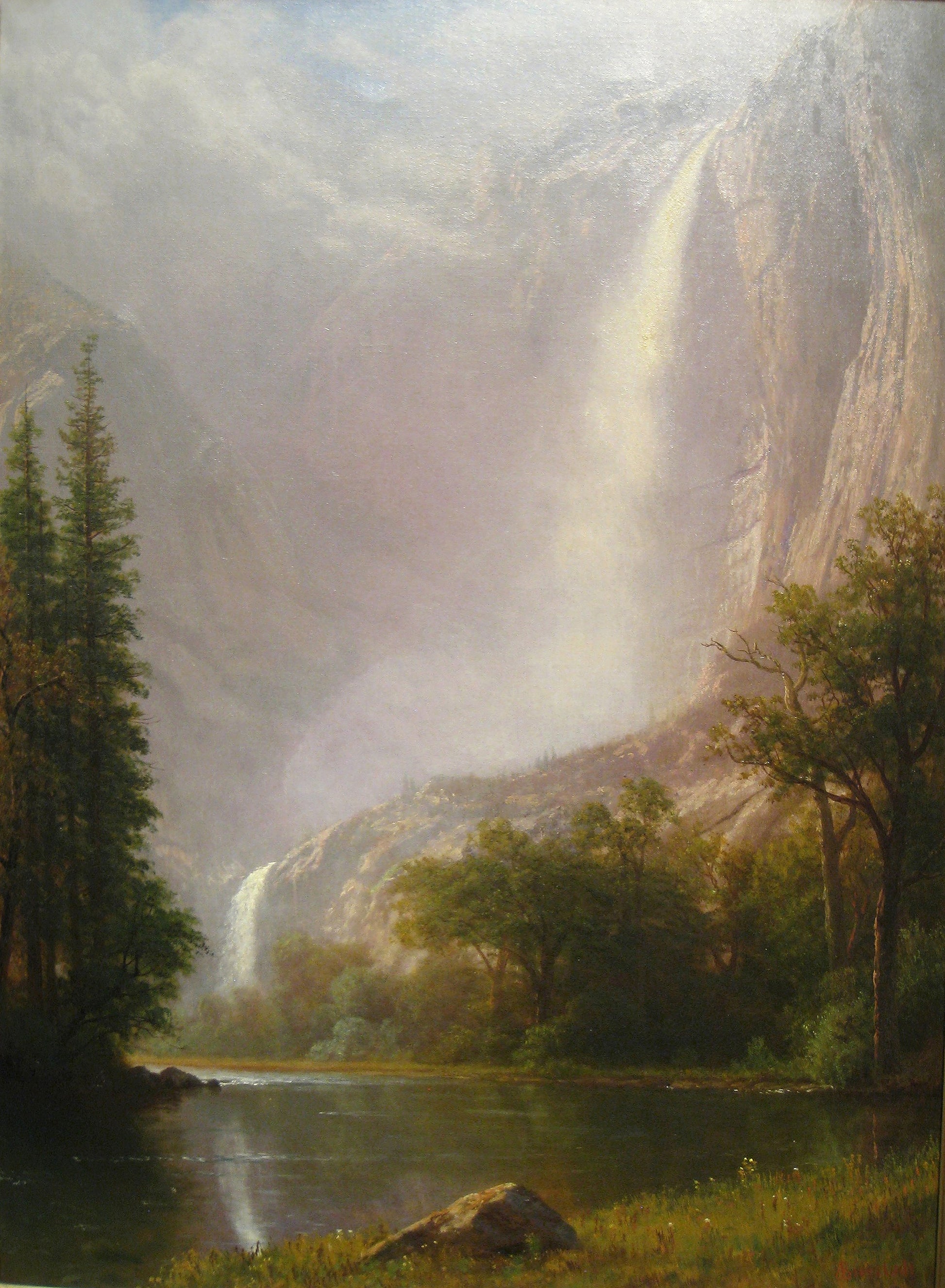 Oil painting of Yosemite Falls by Albert Bierstadt, featuring Yosemite Falls cascading down luminous granite cliffs through mist into a valley with a calm river and green trees below under a cloud-diffused sky.