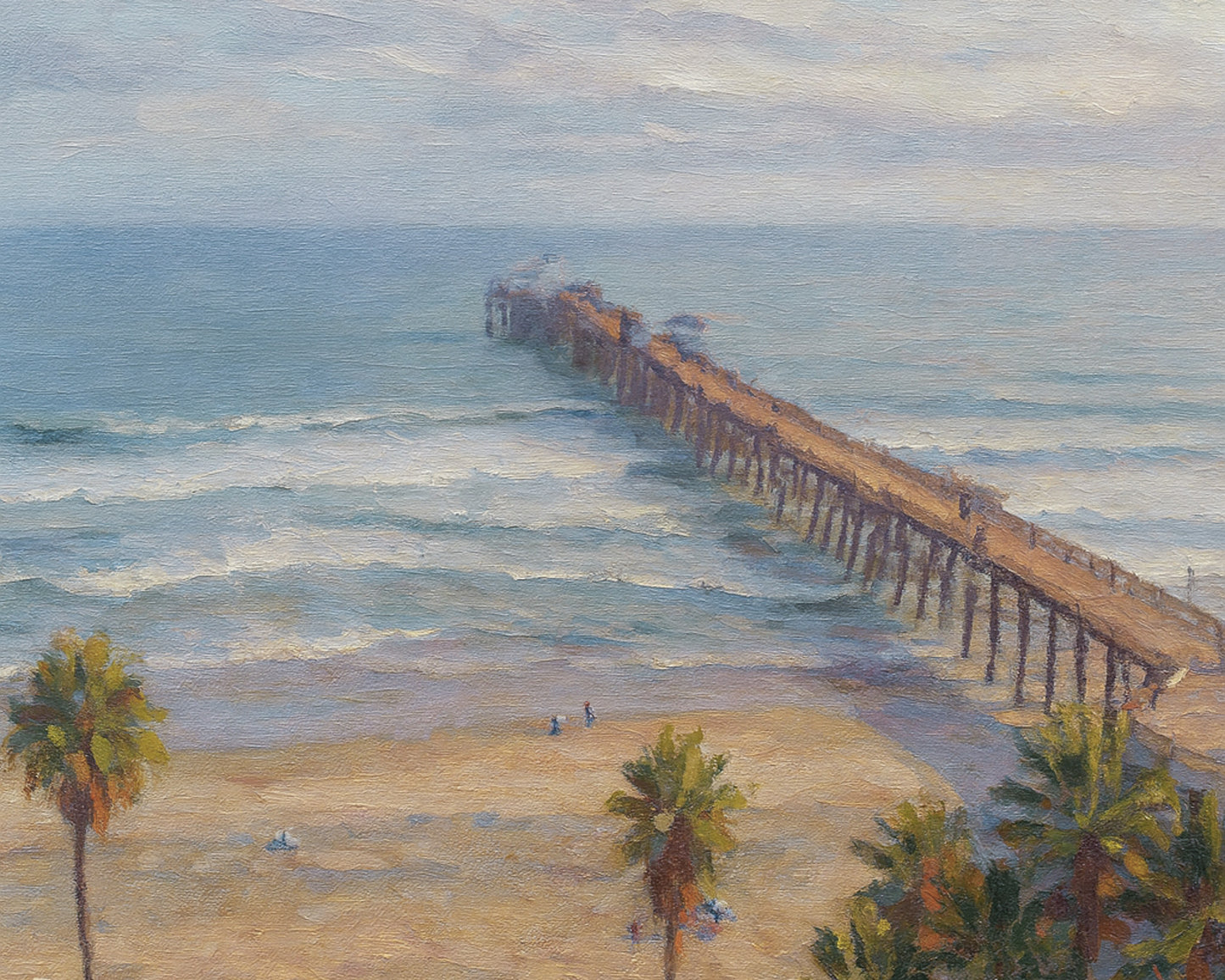 Classic view from the south side of the Oceanside Pier with rolling waves and the coastline stretching into the distance.