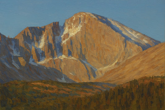 Landscape view of Longs Peak in Rocky Mountain National Park, Colorado, featuring the east face glowing in rich amber and gold light against a clear blue sky with evergreen forest below.